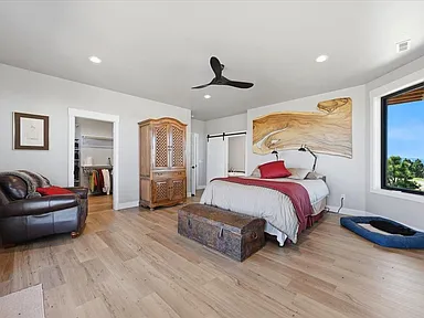 A primary bedroom pairs a leather armchair and a carved wood armoire with a wood-slab headboard and a blue dog bed on the floor.