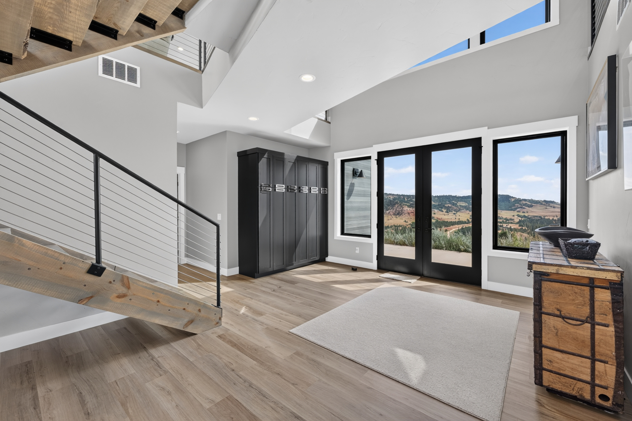 The foyer at 2111 Vantage Circle has tall dark cabinetry beside glass double doors opening to a view of the hills.