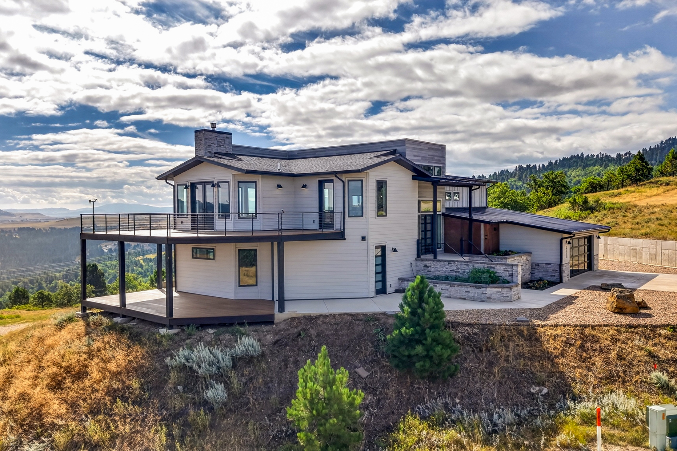 A wraparound deck extends beneath a curved window bay and stone chimney on the rear of 2111 Vantage Circle.